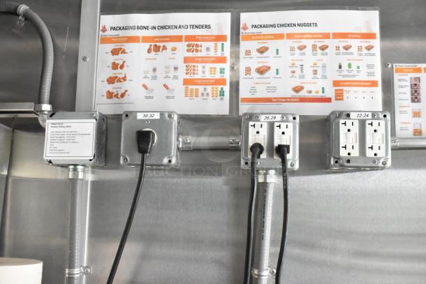 Fully outfitted food trailer interior showing electrical outlets and menu guides for packaging chicken tenders and nuggets.