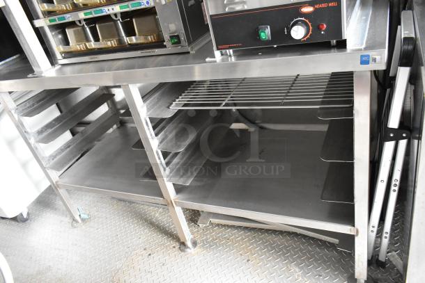 Stainless steel food trailer interior with appliances, shelves, and fixtures. Fully outfitted and ready for use.