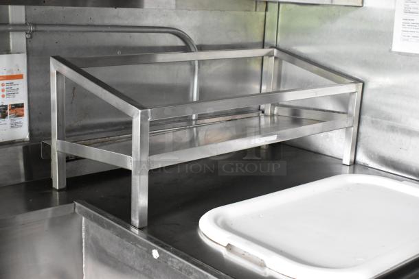 Stainless steel shelf in a food trailer, featuring a sturdy frame and clean surface, ideal for kitchen setup.