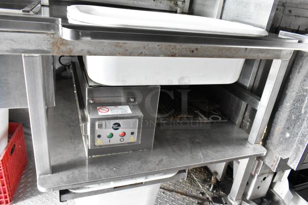 Fully outfitted food trailer interior with stainless steel counter and sink. Visible wear on surfaces. Equipped with a Fry King appliance.