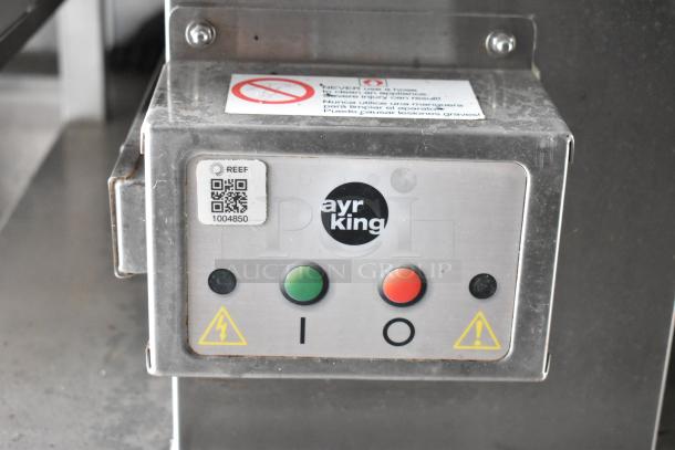 Ayr King control panel with buttons and warning labels on stainless steel surface, part of a food trailer setup.