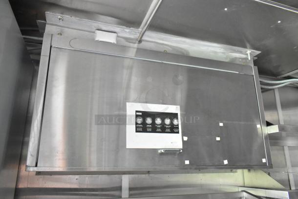 Food trailer interior with stainless steel fixtures and appliances. Label on cabinet door; ready for immediate use.