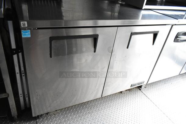 Stainless steel double-door appliance in food trailer, showing Energy Star label. Slight wear visible, essential for commercial use.