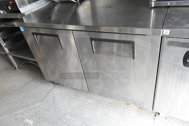 Stainless steel food trailer interior with commercial appliances and storage, showing minor wear, ready for operation.