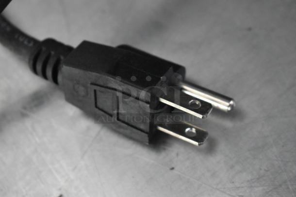 Close-up of a black power plug on a metallic surface, part of a fully outfitted food trailer.