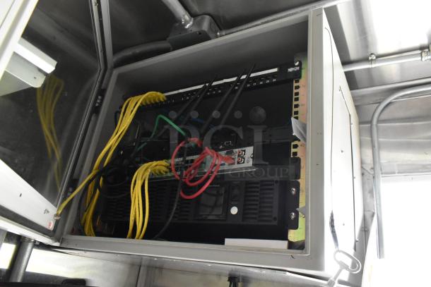 Food trailer interior showing a server rack with cables and equipment, ready for operation. Secure metal frame with labeled network connections.