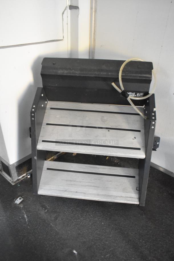 SDG Trailers trailer shelf with two metal racks, black frame, visible tubing, and mounted on a black surface.