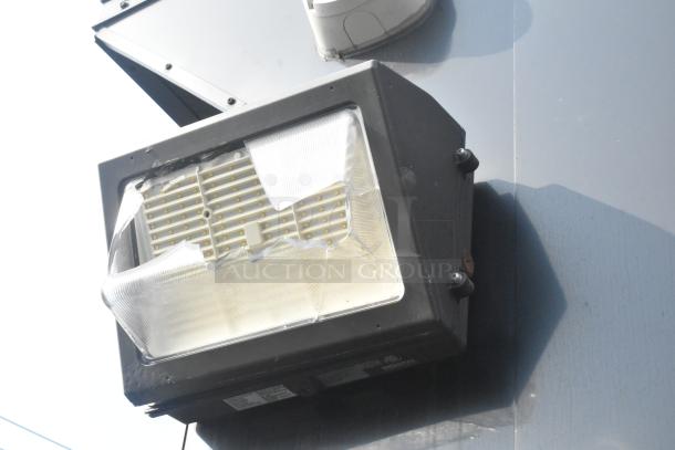 SDG Trailers exterior light fixture with cracked lens, mounted on trailer surface. Scratches visible on the fixture.