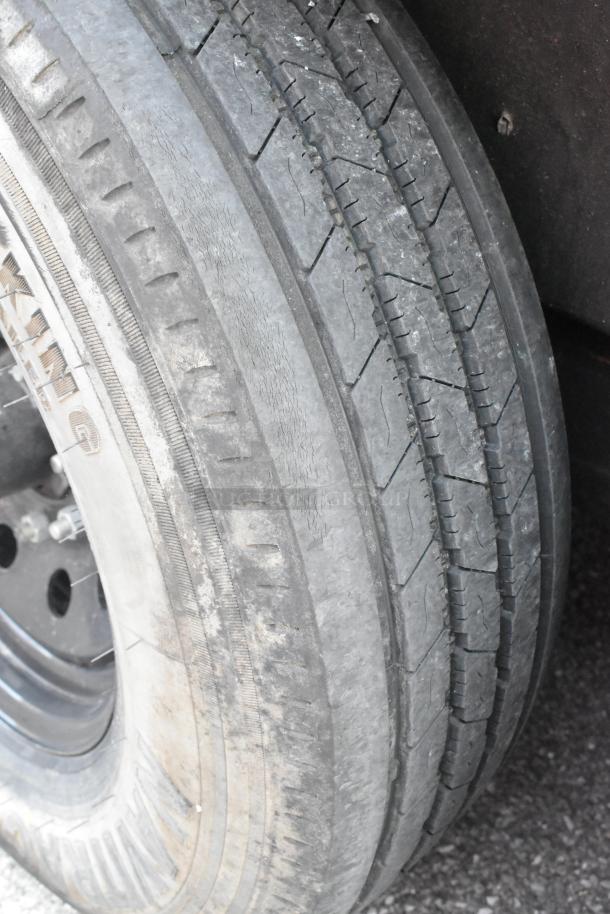 Close-up of an SDG Trailers tire showing tread pattern and sidewall condition. Tire appears used with visible wear.