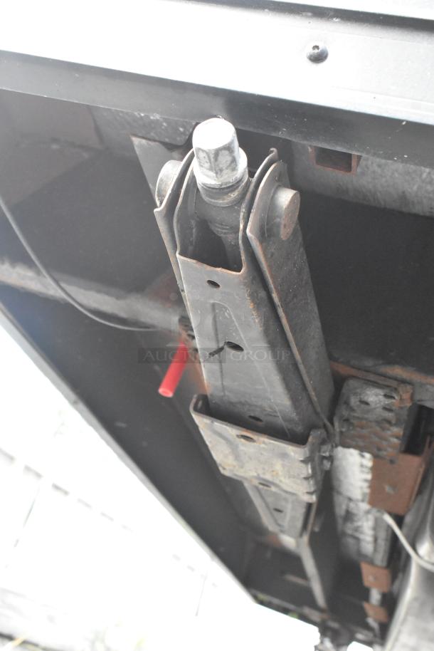 Underneath view of SDG Trailers trailer showing suspension components. Features visible wear and rust.