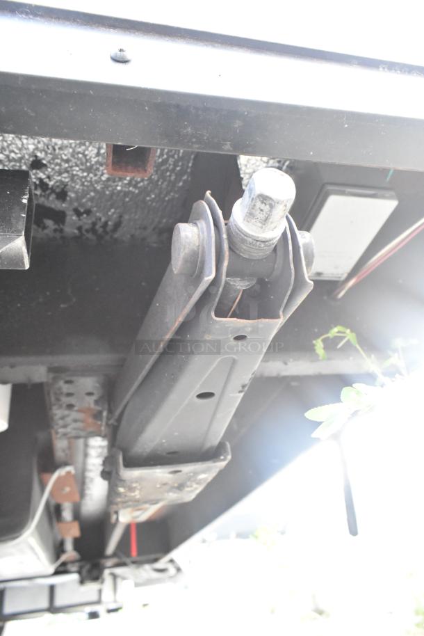 Underside of SDG trailer showing metal components in used condition, focusing on the suspension system and surrounding details.