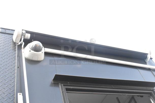 SDG Trailers trailer close-up showing security camera and awning mechanism; diamond plate texture visible on corner.