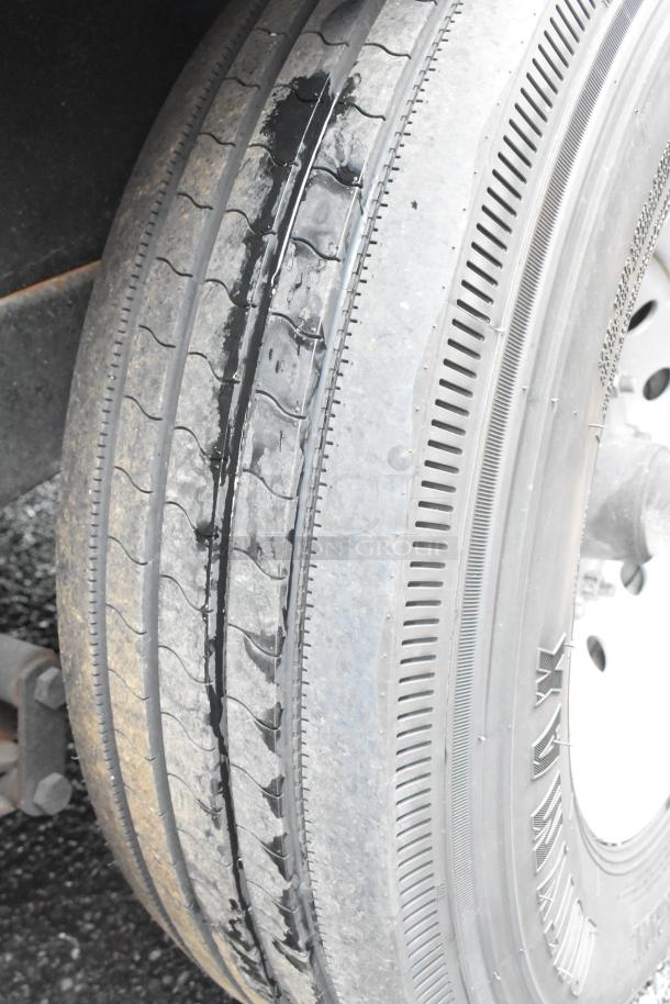 Close-up of a trailer tire with visible wear, mounted on a wheel hub.
