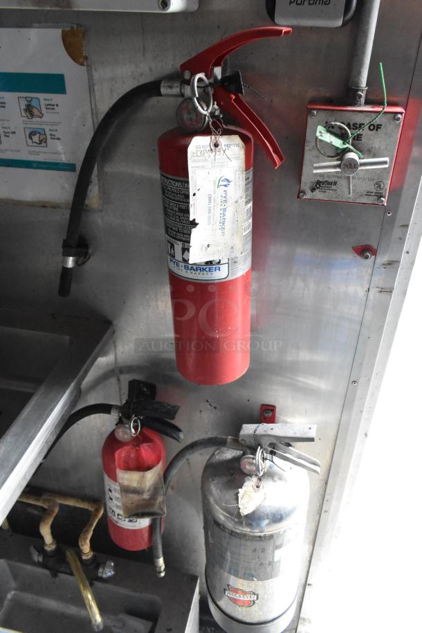 Inside a food trailer, three fire extinguishers and a control panel for safety, featuring Pye-Barker and Buckeye labels.
