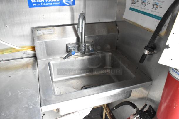 Stainless steel sink with dual tap in a food trailer. Nexel label visible, indicating NSF approval.