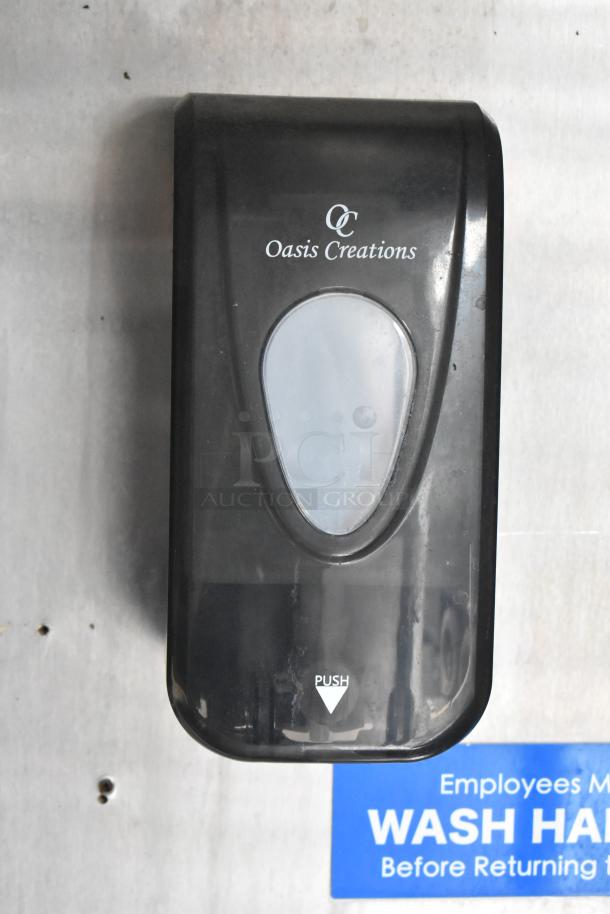 Oasis Creations soap dispenser mounted on a food trailer wall with visible "Wash Hands" warning sign.