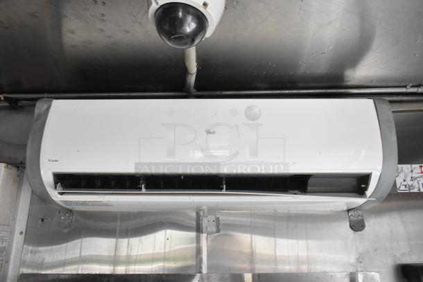 Fully outfitted food trailer interior with mounted air conditioning unit and surveillance camera on stainless steel wall.