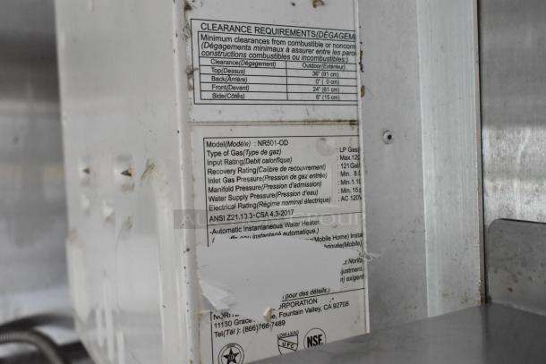 Close-up of a clearance requirement label on a food trailer appliance. Label details model NR501-OD, gas type, and pressure settings.