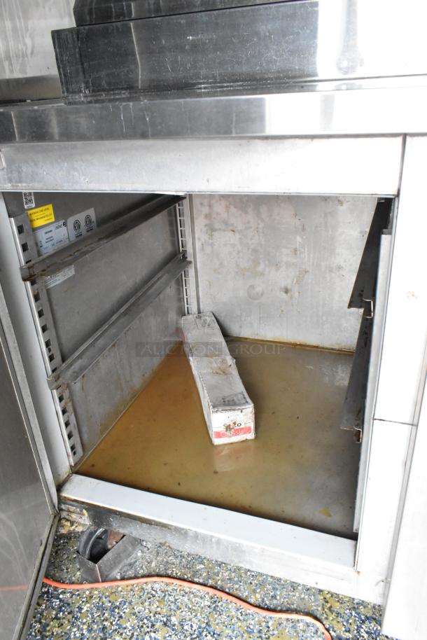 Stainless steel food trailer interior with storage cabinet, showing shelves and a box. Signs of use visible.