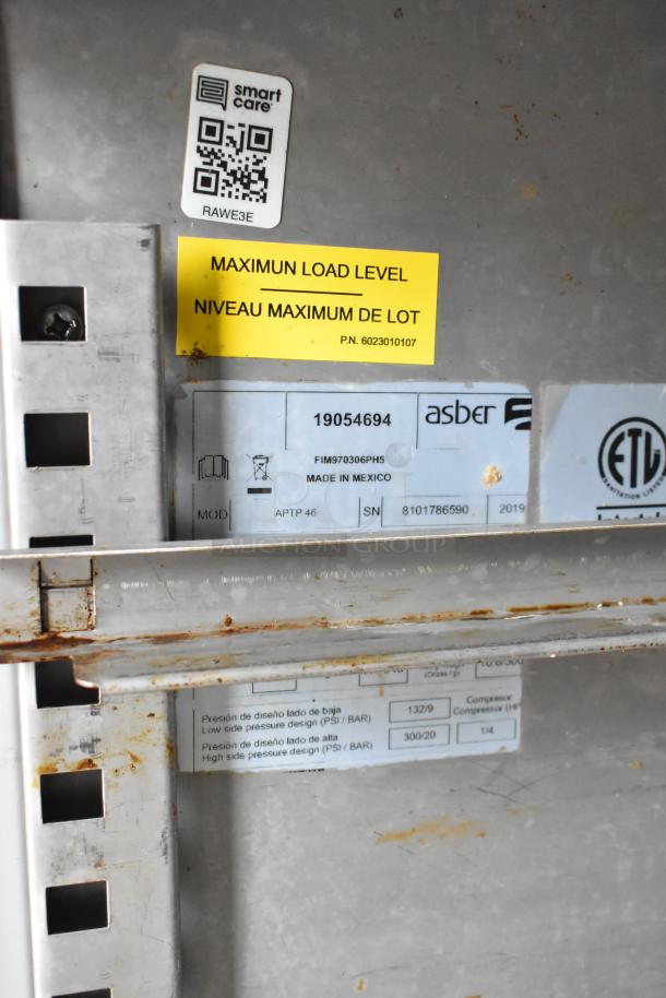 Food trailer interior with shelves, rust spots, and labels. "Maximum Load Level" and Asber model 19054694 notes visible.