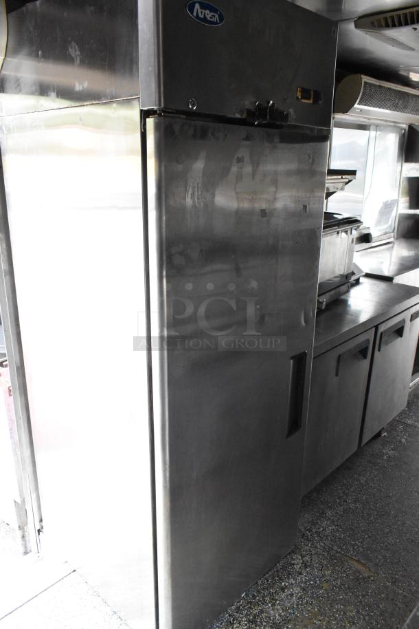 Stainless steel Atosa refrigerator in food trailer, featuring sleek design and commercial-grade construction.