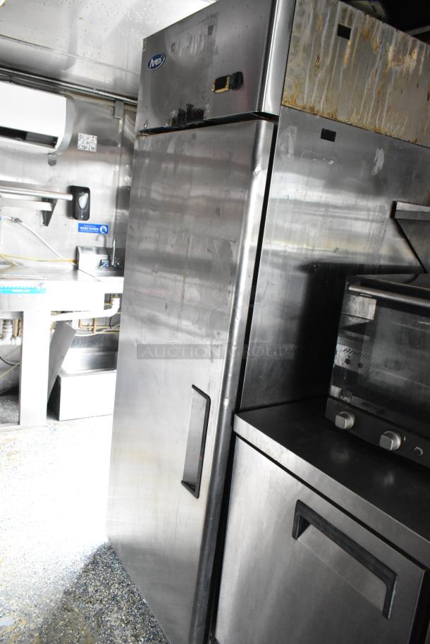 Stainless steel food trailer interior with fridge and oven, clean condition, featuring appliance fixtures for a food service setup.