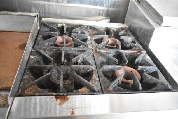 Industrial-grade stovetop in More Than A Dream food trailer, featuring four burners and a grill, showing signs of use.