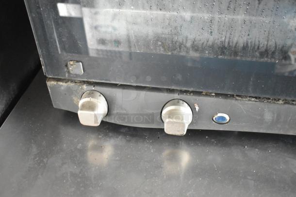 Oven control panel in food trailer with two knobs showing temperature settings and a blue button, slight wear visible.