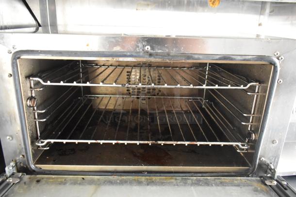 Interior of a stainless steel food trailer oven, showing two wire racks. Oven appears clean and well-maintained.