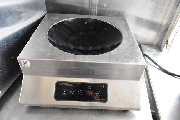 Stainless steel Adventys induction cooker in a food trailer, black glass top, digital controls, "Made in France" label.