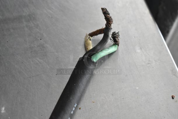 Damaged electrical wire with exposed copper strands on a metal surface, indicating wear and potential for a needed repair.