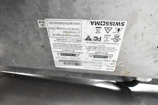 Label showing appliance details: Swiss Made, model number, AC specifications, and safety warnings.