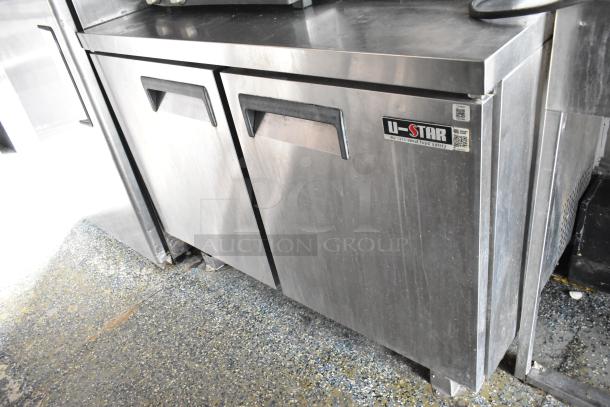 Stainless steel U-Star commercial refrigerator in a food trailer, featuring dual doors and label for food safety compliance.