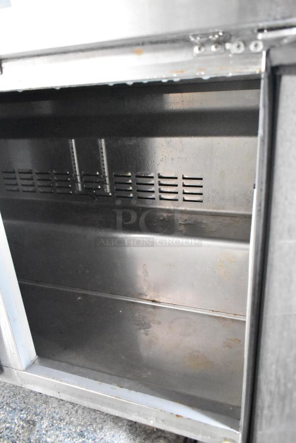 Stainless steel interior of food trailer showing storage compartment, slightly worn but clean. Ready for use.