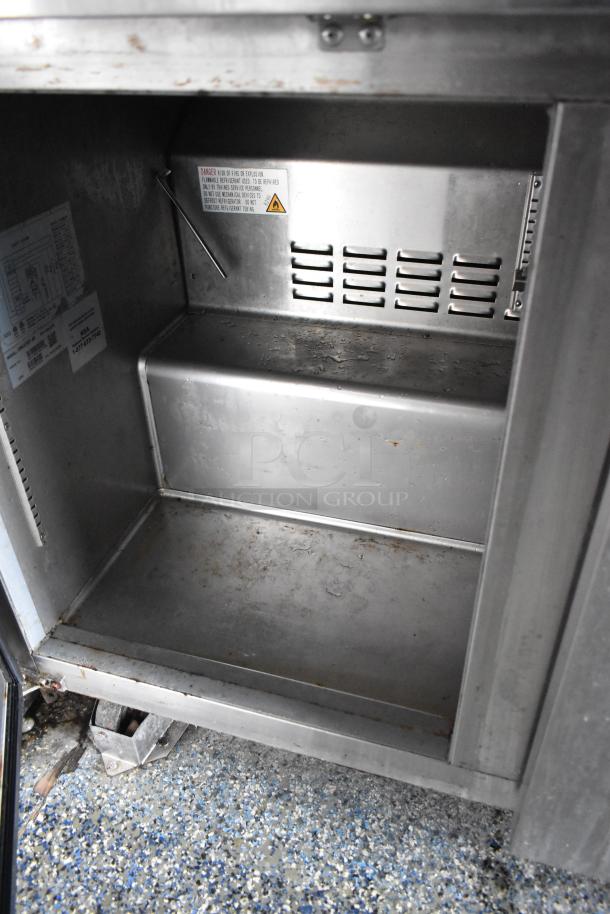 Stainless steel interior of a food trailer with labels indicating model and safety warnings. Slight wear visible.