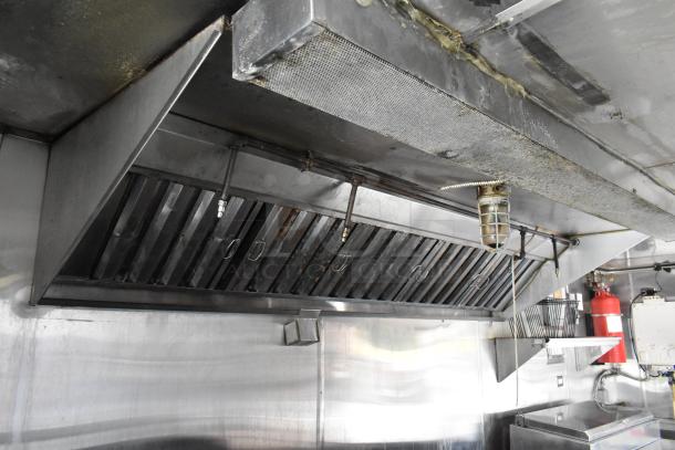 Fully equipped food trailer interior with commercial exhaust hood, stainless steel fixtures, and fire safety equipment.