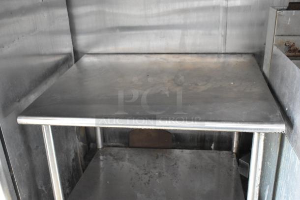 Stainless steel counter inside a food trailer, showing signs of use, indicating durable kitchen setup.
