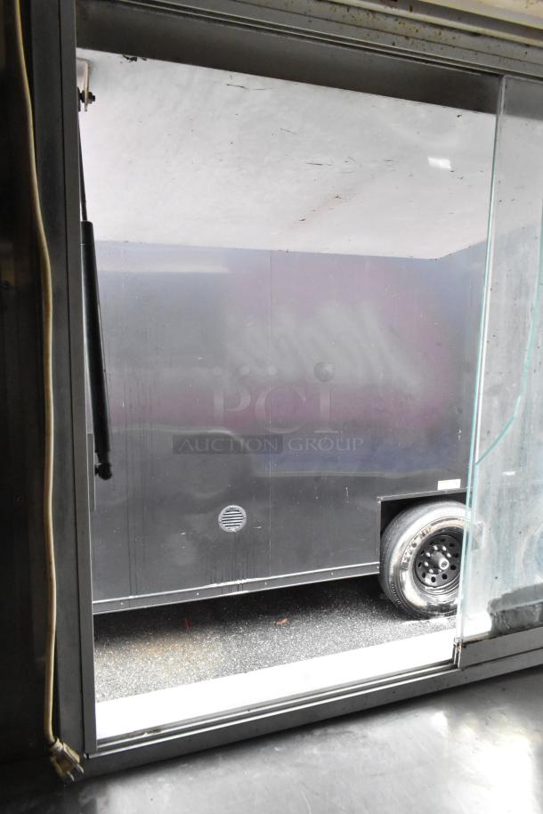 Food trailer interior window view, showing black exterior and wheel. Ready for operation, detailed appliances included.