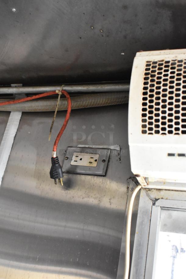 Interior view of a food trailer showing an electrical outlet and a nearby appliance. Clean, functional condition.