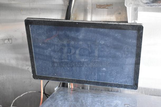 Touchscreen monitor installed in a food trailer, showing some dust and mounted on a stainless steel wall.