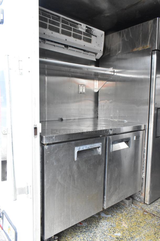 Stainless steel food trailer interior with fridge, shelving, and air vent. Ready for opening day, clean and fully outfitted.
