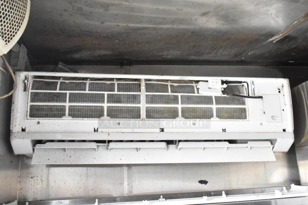 Interior view of a food trailer showing an installed wall-mounted air conditioning unit with a protective grille; appears used.