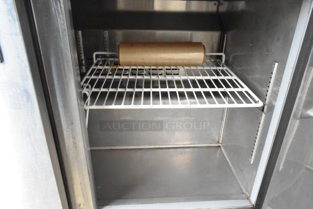 Interior view of stainless steel food trailer, showing a clean metal shelf with a roll of parchment paper, showcasing ample storage space.
