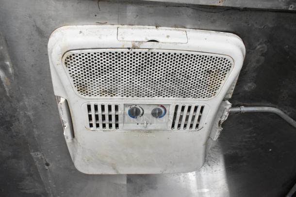 Dometic ceiling-mounted vent fan with temperature controls in a food trailer, showing some wear and grime.