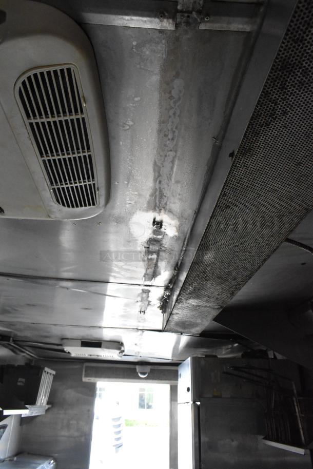 Interior view of a fully outfitted food trailer with appliances, ventilation system, and stainless steel fixtures.
