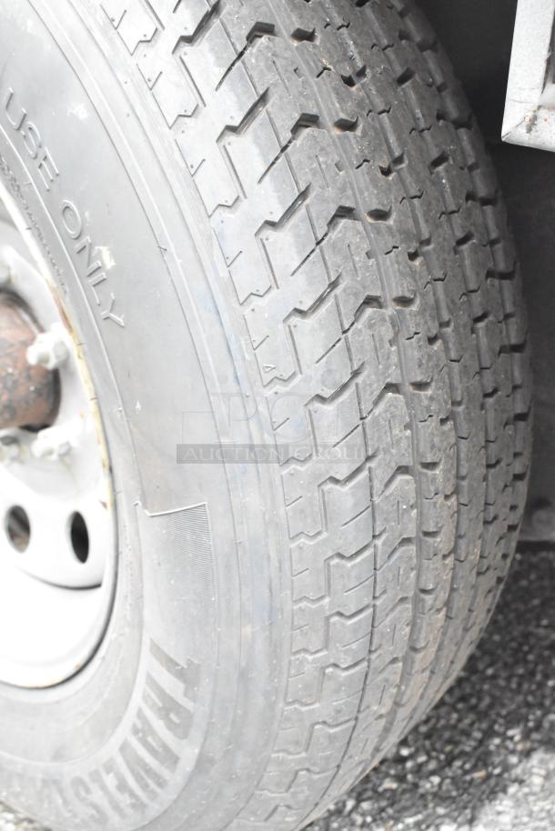 Close-up of a food trailer tire in good condition. Tread pattern visible, labeled "Trailer Use Only" and "ST" mark.