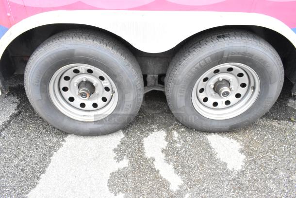 Twin wheels of a food trailer, featuring robust steel rims with Traveler Star tires for trailer use, indicating durability.