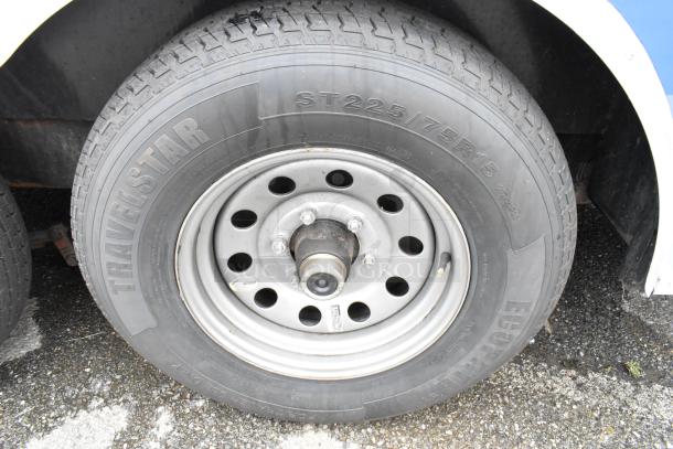 Travelstar tire on food trailer, model ST225/75R15, mounted on a multi-hole steel rim. Tire appears in good condition.