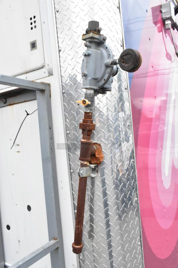 Outdoor gas regulator and piping on a food trailer exterior with diamond plate metal finish. Functional and ready for use.