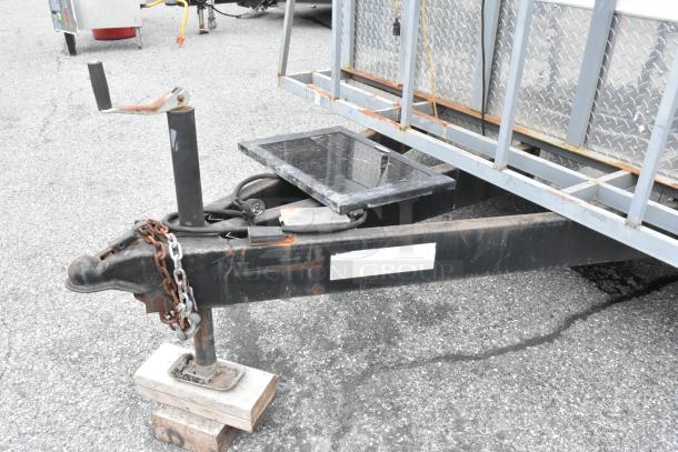 Trailer hitch of a fully outfitted food trailer, featuring sturdy build and chains. Ready for operation, ideal for food business.